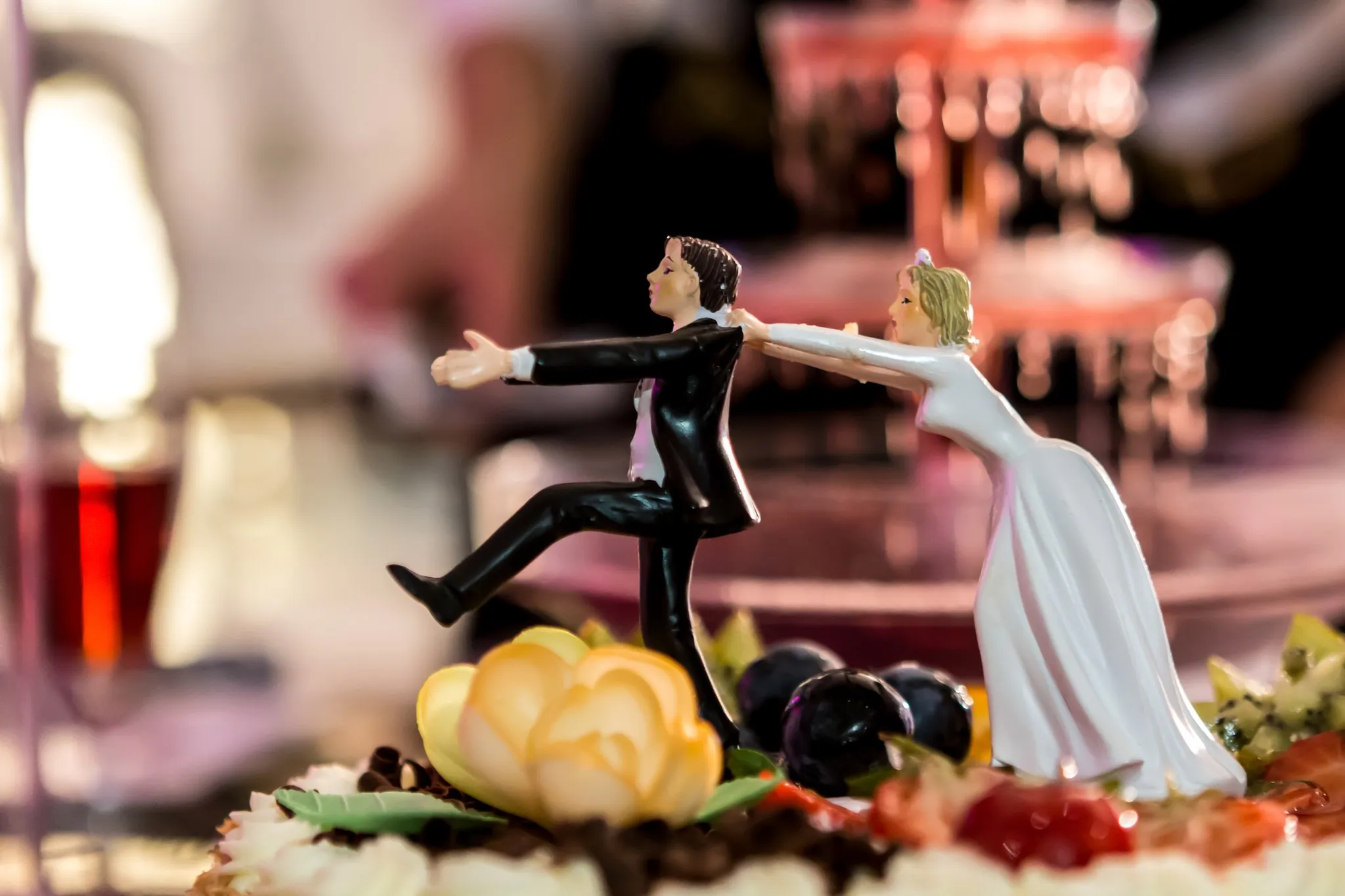 Bruidstaartfiguurtjes op een met fruit afgewerkte taart tijdens een huwelijksfeest